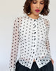 Model trägt einen weißen Mesh Cardigan mit schwarzem Polkadotprint zu einer schwarzen Ballonrock.