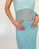 Model trägt einen blauen Spitzenrock mit Blumenstruktur zu einem dazu passenden Oberteil auch in blauer Spitze mit Blumenstruktur.